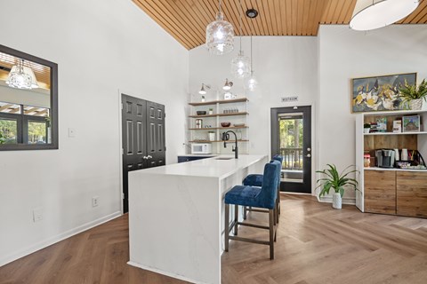 A kitchen with a white island and blue chairs.
