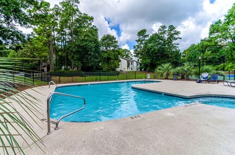 A swimming pool surrounded by a fence and trees.