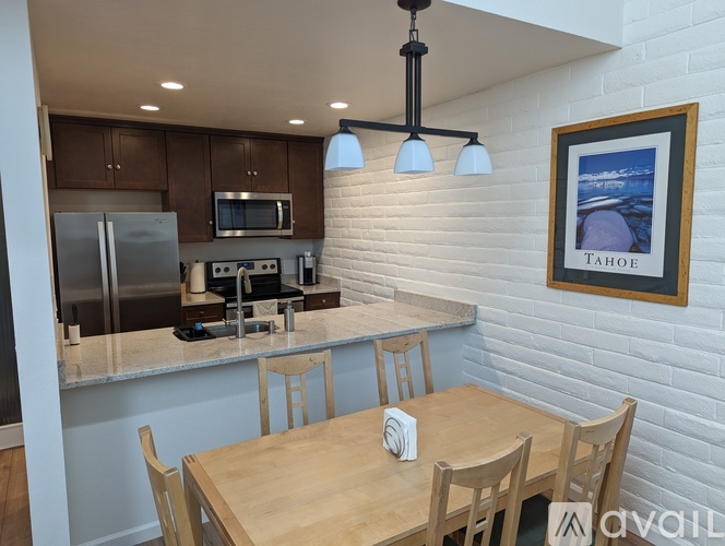 A kitchen with a dining table and chairs and a framed picture of Tahoe on the wall.