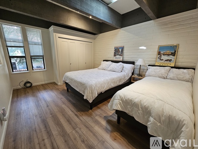 A bedroom with two beds and wooden floors.