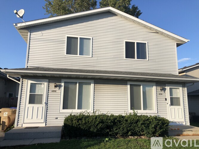 A house with a grey siding and a white door is for sale.