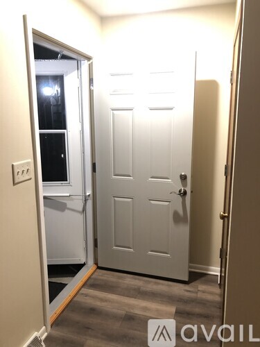 A white door is in a room with a light switch on the wall.
