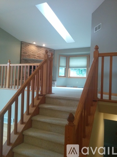 A staircase with wooden railings leads to a brightly lit room.