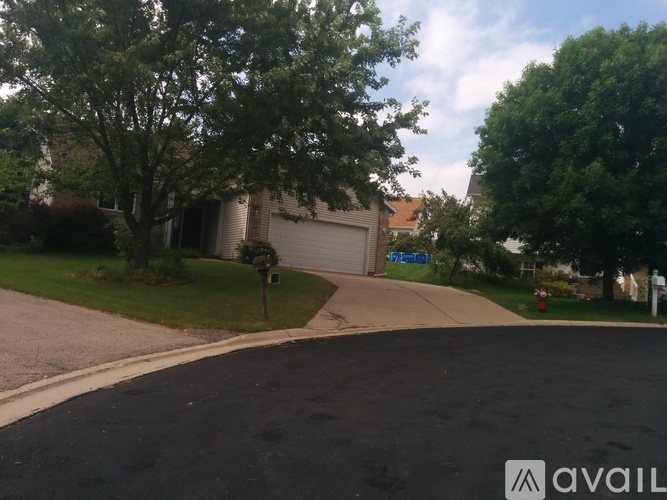 A residential street with a house and trees on the side.
