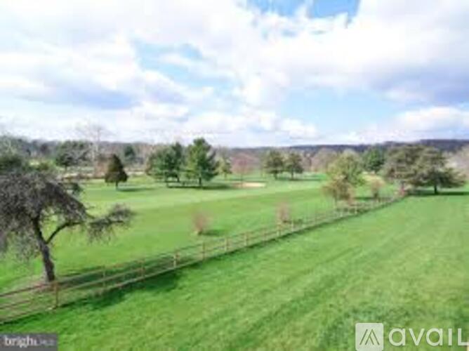 A grassy field with a fence and trees in the distance.