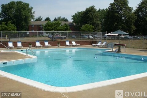 A large swimming pool surrounded by a fence and lounge chairs.