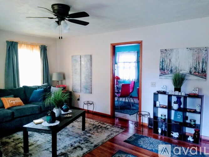 A living room with a green couch, a black coffee table, and a ceiling fan.