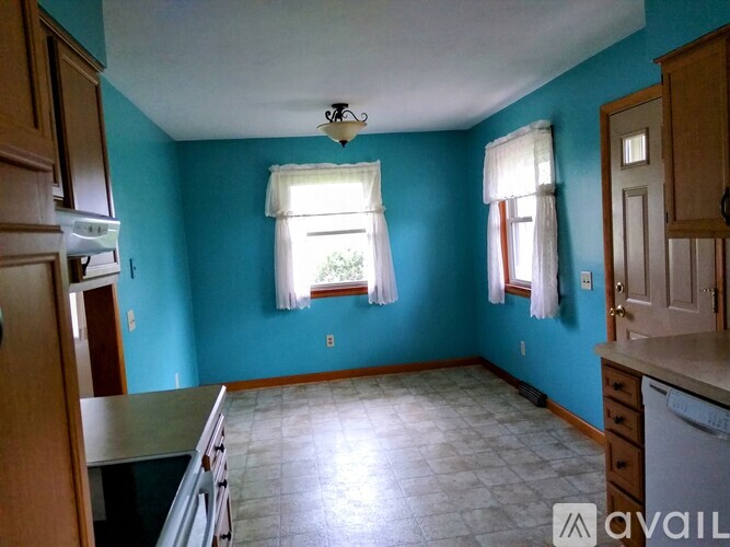 A kitchen with blue walls and a window with white curtains.