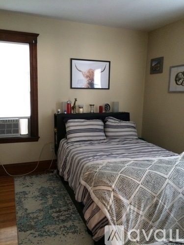 A bedroom with a bed, a window, and a picture on the wall.