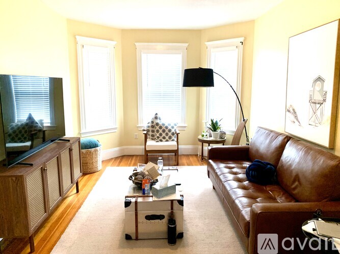 A living room with a brown leather couch, a coffee table, and a television.