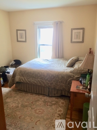 A bedroom with a bed, nightstand, and window.