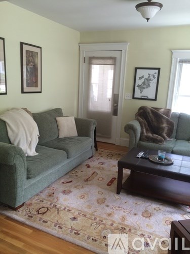 A living room with a green couch, a brown coffee table, and a rug with a floral pattern.