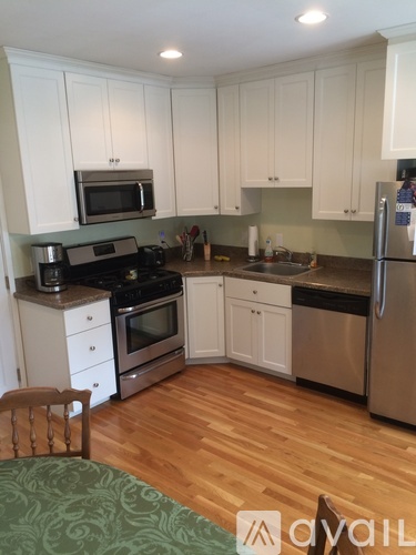 A kitchen with white cabinets and a green patterned chair.