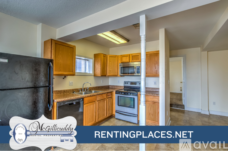 A kitchen with a black fridge and wooden cabinets is on the market.