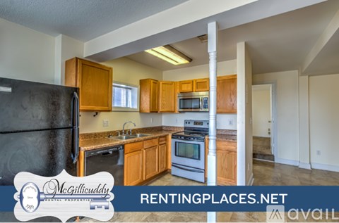 A kitchen with a black fridge and wooden cabinets is on the market.