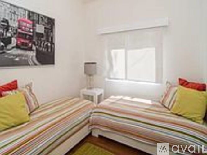 A bedroom with a bed and a picture of a double decker bus on the wall.
