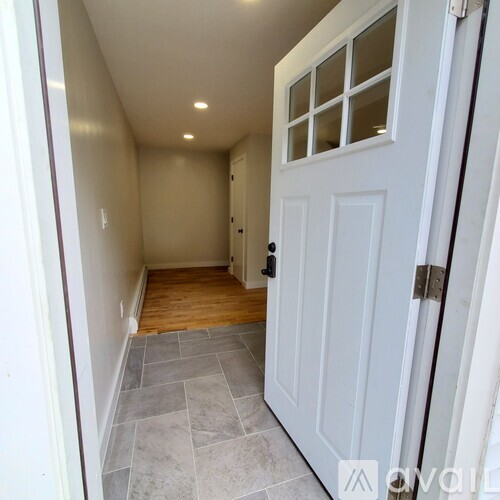 A hallway with a white door and a tiled floor.