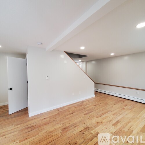 A room with wooden flooring and white walls.