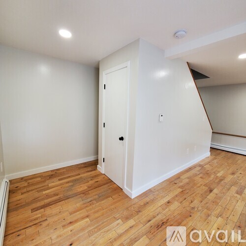 A room with a white door and wooden flooring.