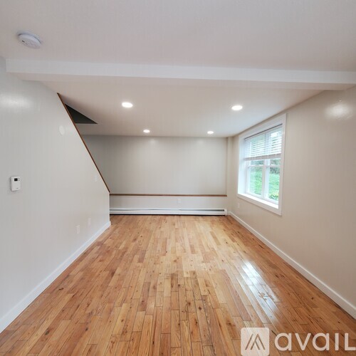 A room with wooden flooring and a window on the wall.
