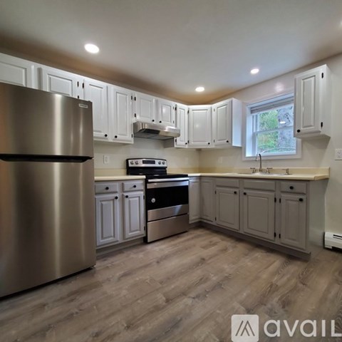 A kitchen with a stainless steel refrigerator and wooden flooring.