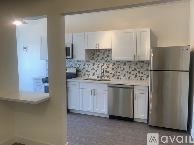 A kitchen with white cabinets and a stainless steel refrigerator.
