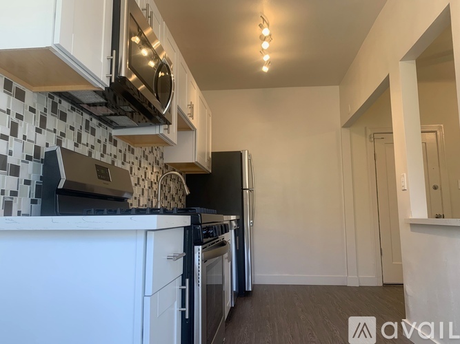 A kitchen with black and white tiles and stainless steel appliances.
