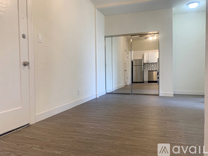 A spacious room with wooden flooring and a white door.