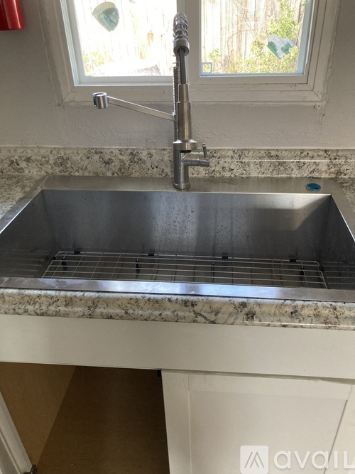 A kitchen sink with a chrome faucet and a window above it.