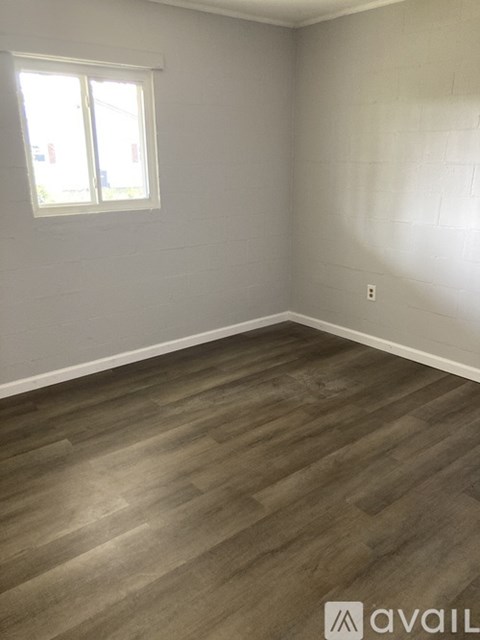 A room with wooden flooring and a window.