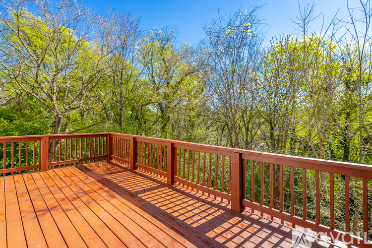 A wooden deck with a railing and trees in the background.