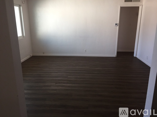 A room with wooden flooring and white walls.