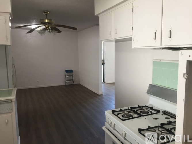 A kitchen with a white stove and a fan on the ceiling.
