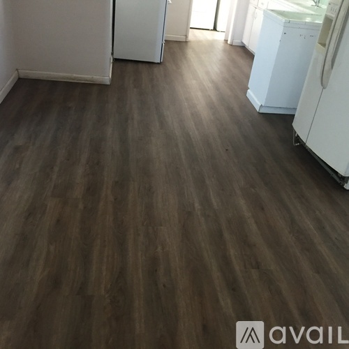 A kitchen with white appliances and wooden floors.
