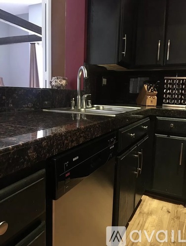 A kitchen with black cabinets and a granite countertop.
