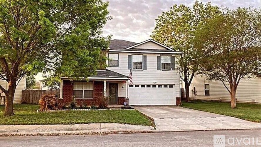 A two-story house with a garage is surrounded by a well-maintained lawn and trees.