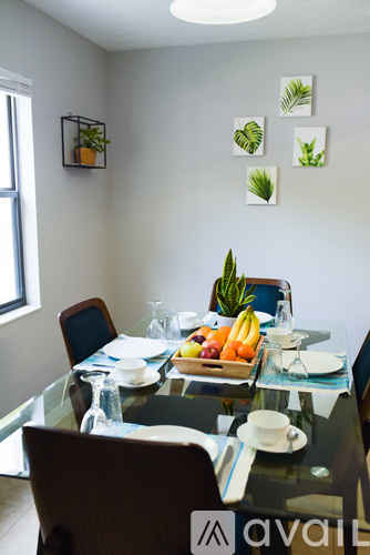 A glass dining table with a tray of fruit and a plant on it.