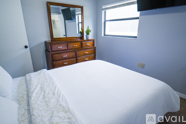 A bedroom with a large bed, a dresser with a mirror, and a window.