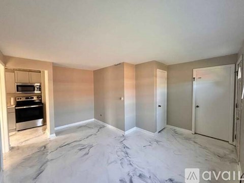 A spacious room with marble flooring and a kitchen area with a stove and oven.