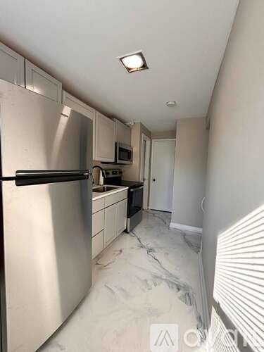 A kitchen with a refrigerator, microwave, and sink.