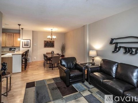 A living room with a black leather couch and a dining table with chairs.
