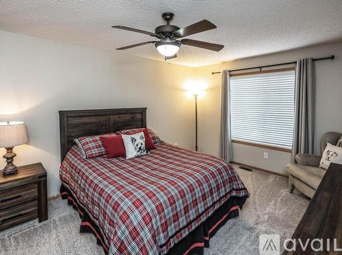 A bedroom with a bed, a ceiling fan, and a window with blinds.