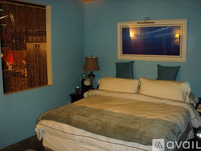 A bedroom with a large bed and a painting on the wall.