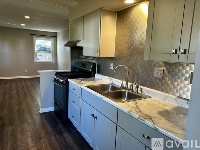 A kitchen with a sink, stove, and cabinets.
