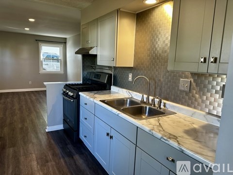 A kitchen with a sink, stove, and cabinets.
