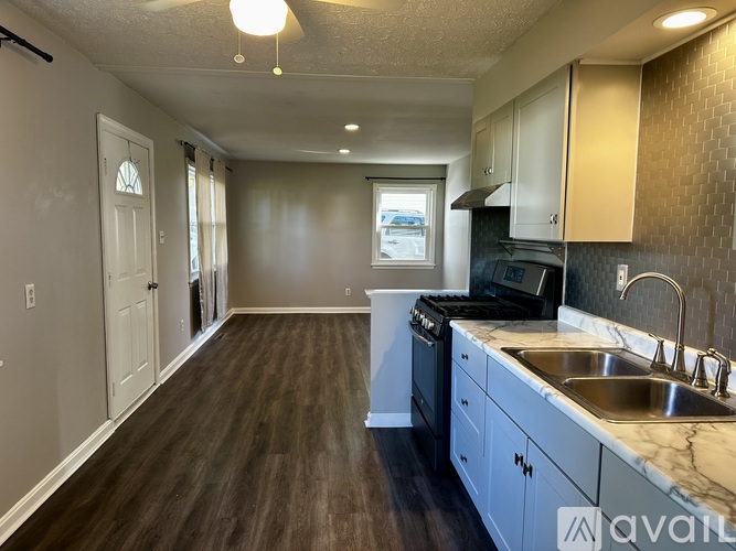 A kitchen with a sink, stove, and cabinets.