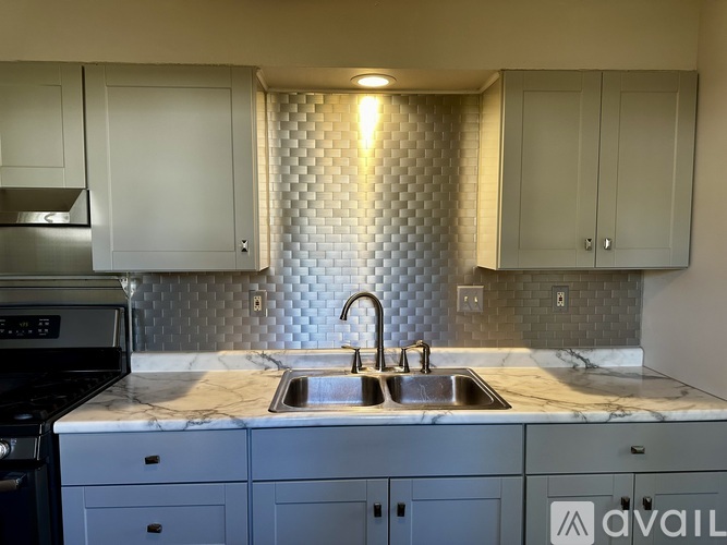 A kitchen with a marble countertop and a backsplash of hexagonal tiles.