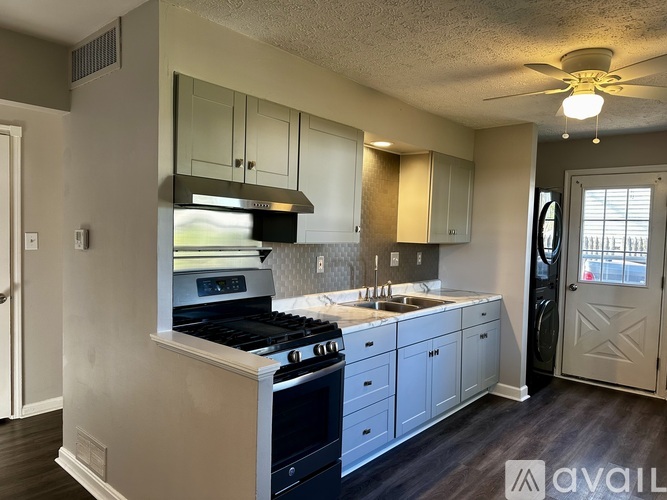 A kitchen with a stove, sink, and cabinets.