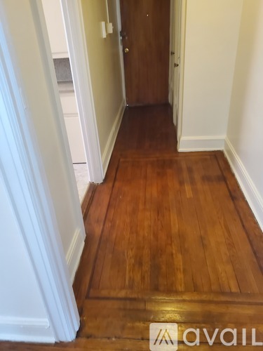 A hallway with a wooden floor and white walls.