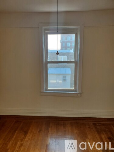 A window in a room with wooden floors and white walls.